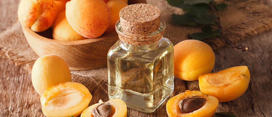 A bottle of cold-pressed apricot kernel oil among fresh apricots