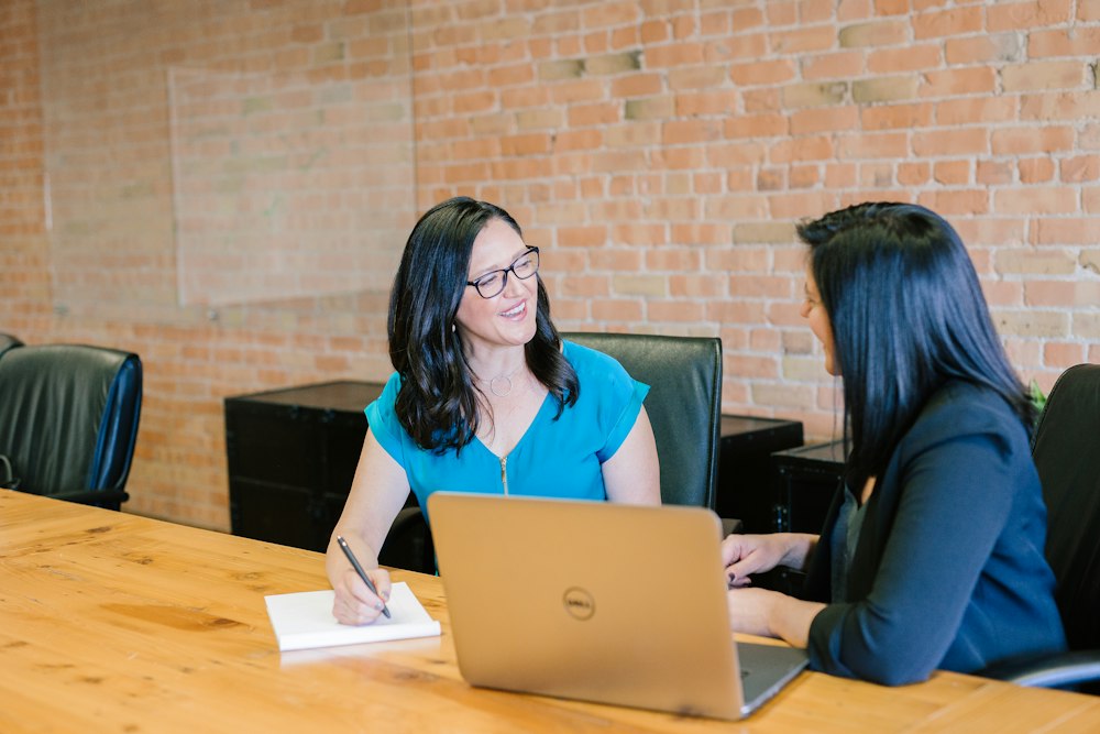A consultant advising a client across a laptop in a meeting room