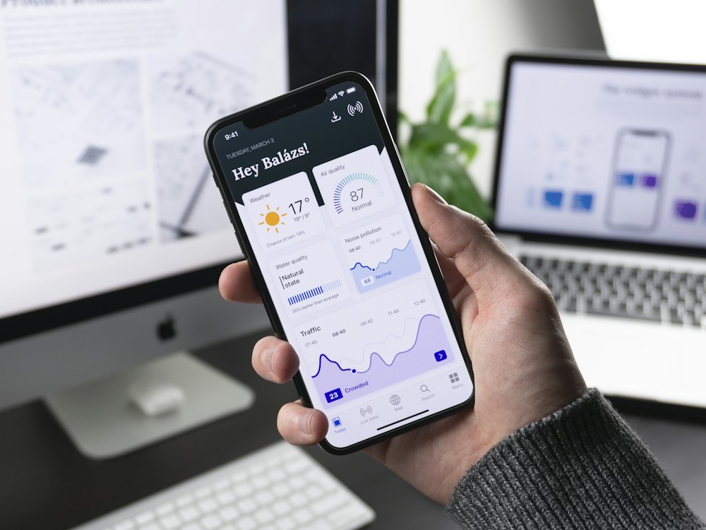A mobile app interface running on a phone beside its design screens